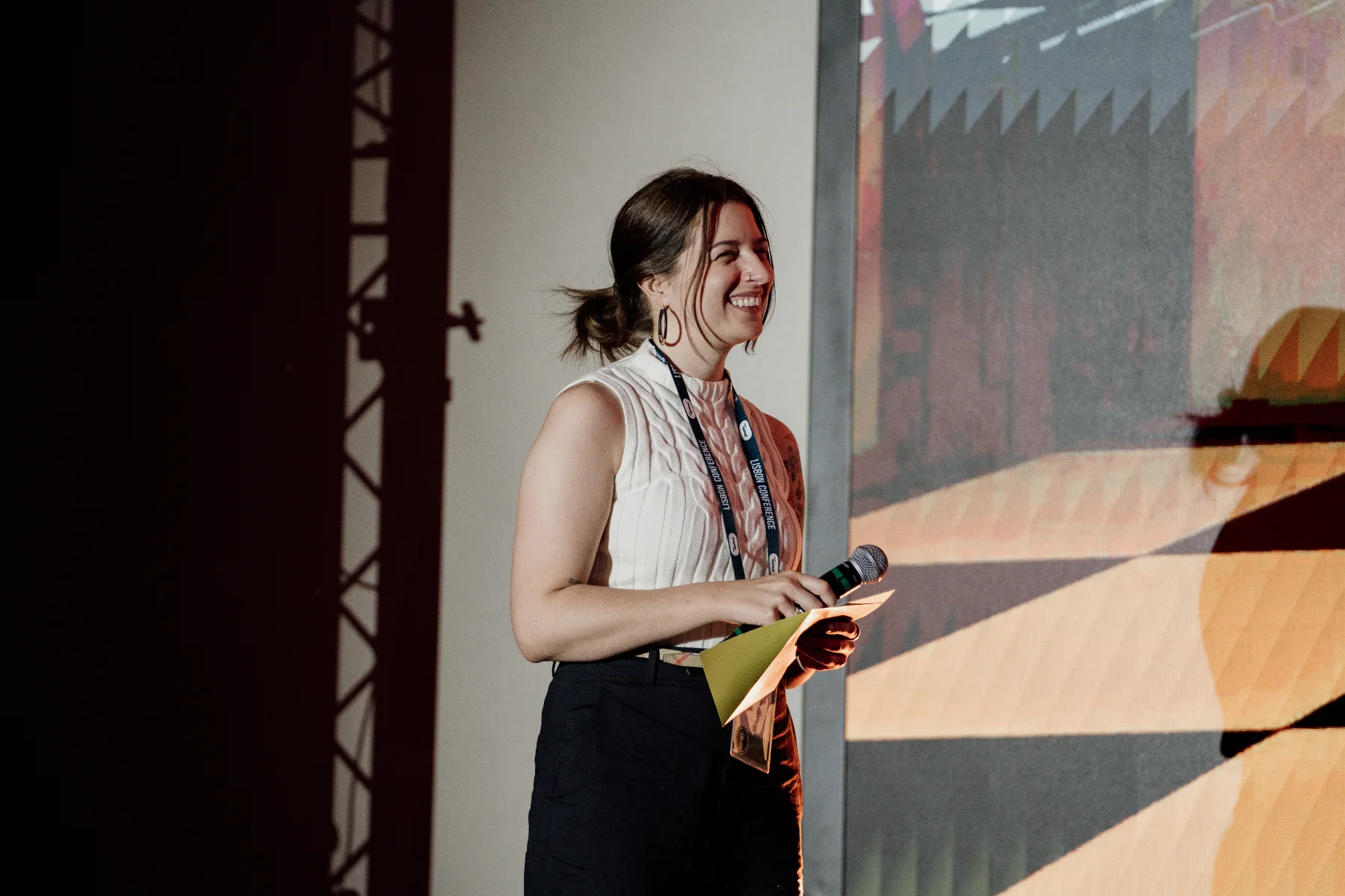 Abby on stage at a conference in Lisbon, laughing with a microphone in hand