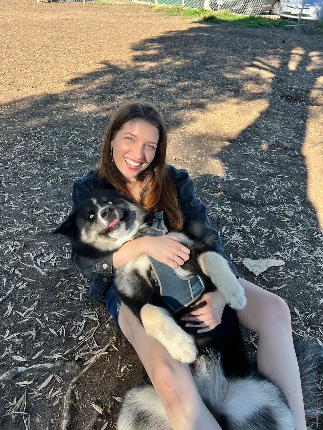 Abby sitting in a park, holding a fluffy black-and-white dog
